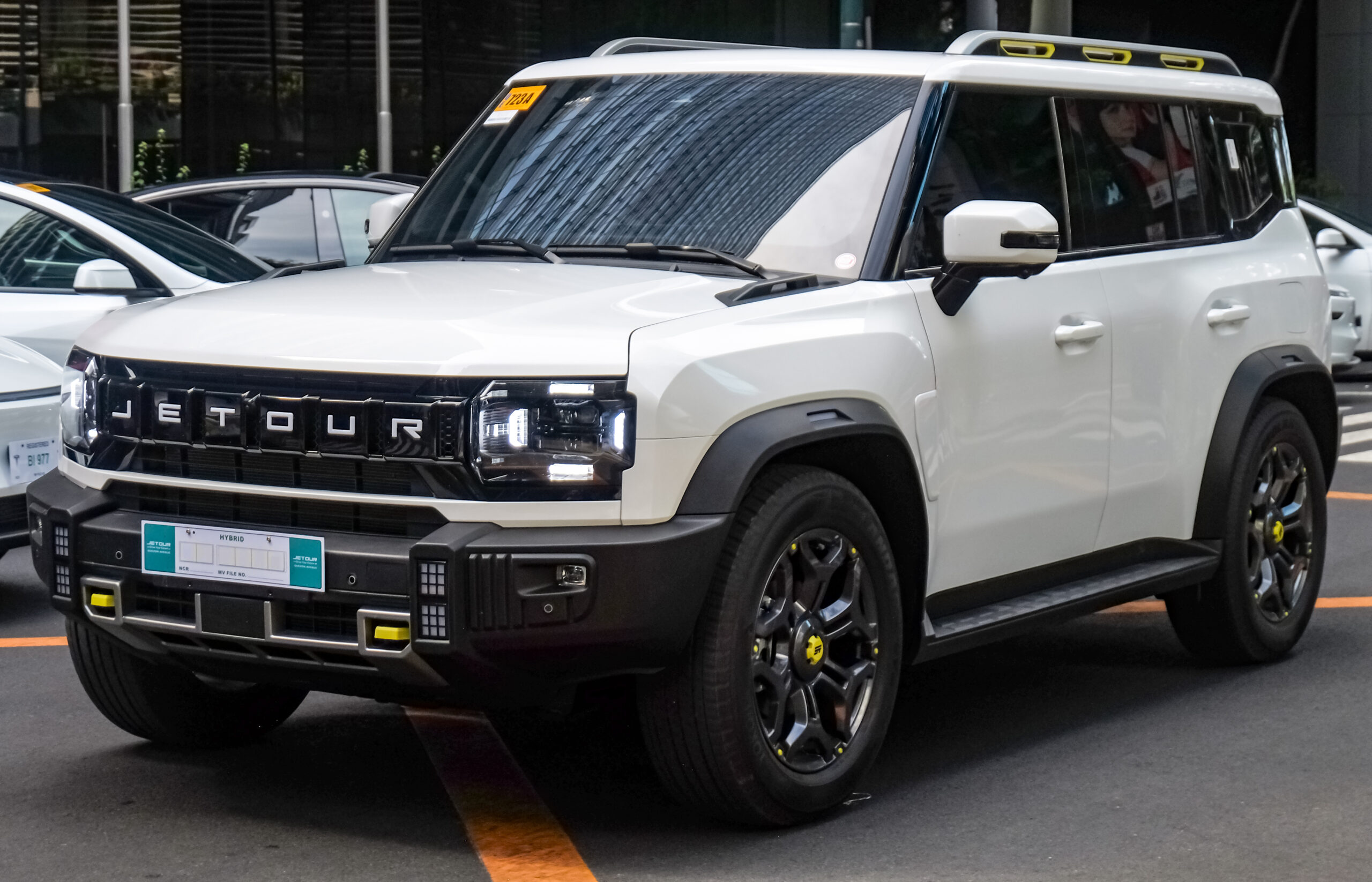Jetour T2 PHEV 2026 tampilan samping depan di area mixed terrain dengan latar belakang urban